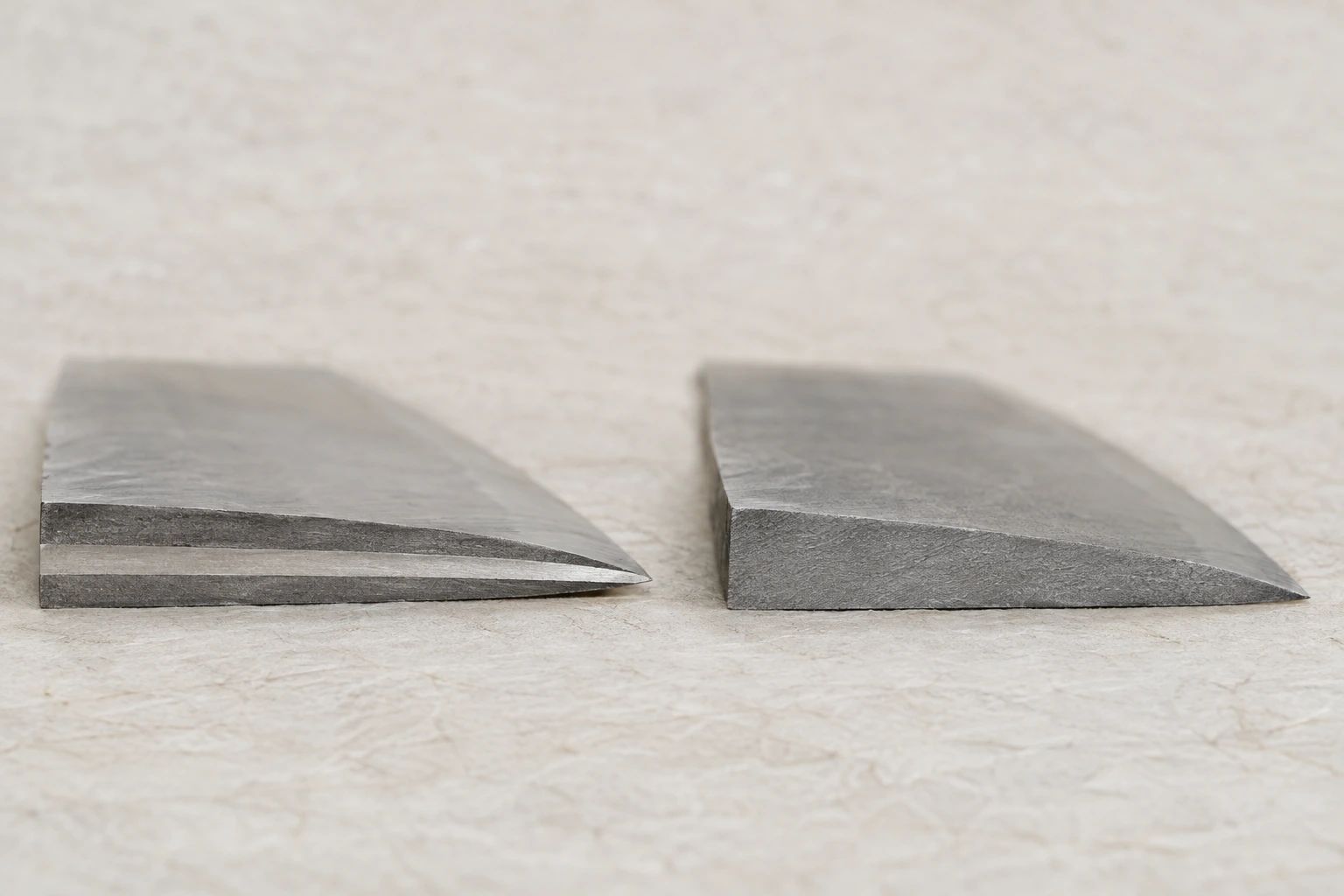 Cross-sections of two blade blanks on washi: a laminated one with a visible seam and a solid one of uniform steel